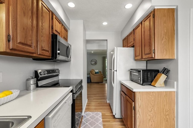 1702 Lewis O Gray Dr Unit 1702, Saugus, MA 01906 - kitchen featuring stainless steel appliances, light wood-style floors, light countertops, brown cabinetry, and recessed lighting