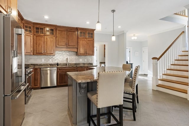 kitchen with appliances with stainless steel finishes, sink, pendant lighting, stone countertops, and a center island