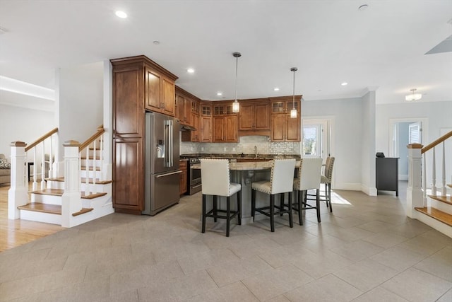 kitchen with light stone countertops, a center island, high end refrigerator, stove, and pendant lighting