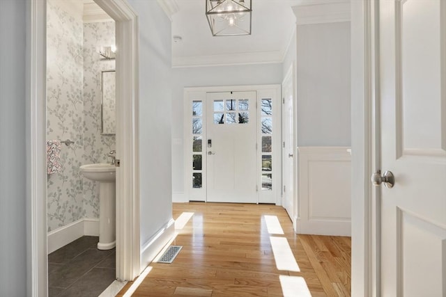 entryway with light hardwood / wood-style floors, an inviting chandelier, ornamental molding, and sink