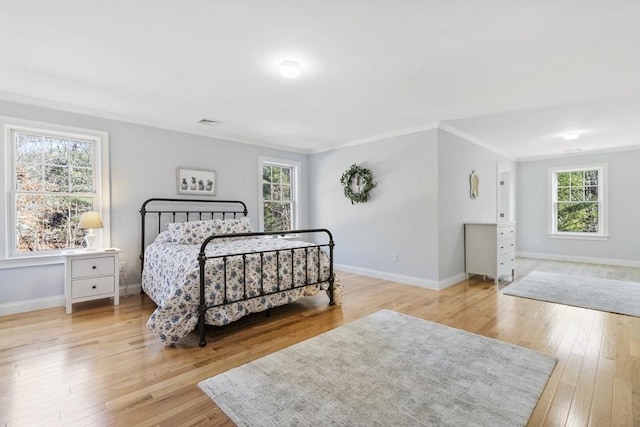 bedroom with light wood-type flooring, multiple windows, and ornamental molding