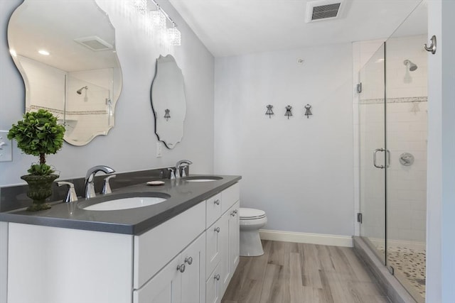 bathroom with wood-type flooring, vanity, toilet, and a shower with door