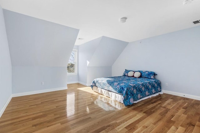 bedroom with lofted ceiling and wood-type flooring