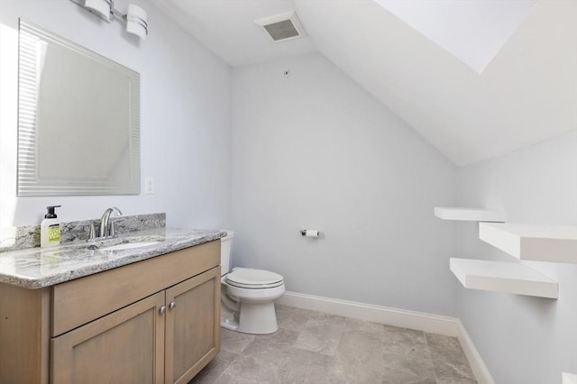 bathroom featuring vanity, toilet, and vaulted ceiling