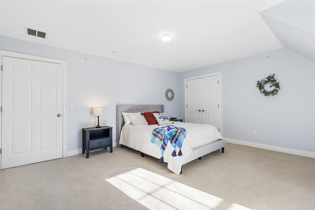 bedroom featuring light colored carpet, lofted ceiling, and a closet