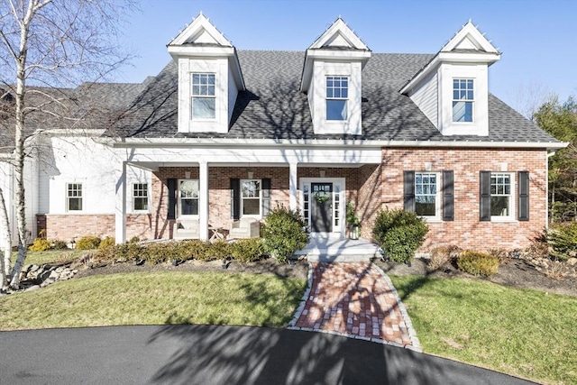 cape cod house with a front lawn and covered porch