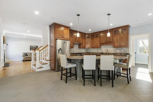 kitchen featuring a center island, high end fridge, light stone countertops, and hanging light fixtures