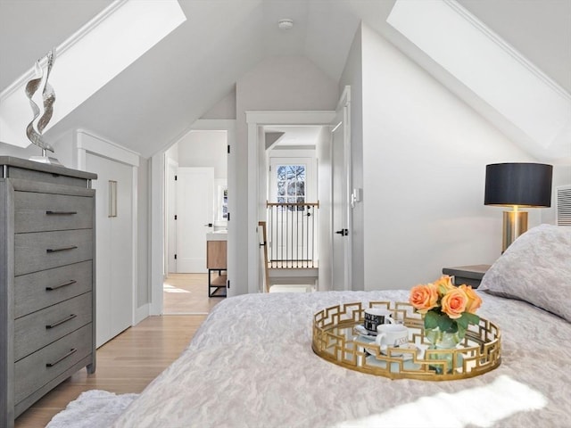 bedroom featuring lofted ceiling with skylight and light wood-type flooring