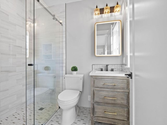 bathroom with vanity, toilet, a shower with shower door, and decorative backsplash