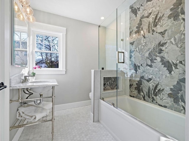 full bathroom with sink, bath / shower combo with glass door, and toilet