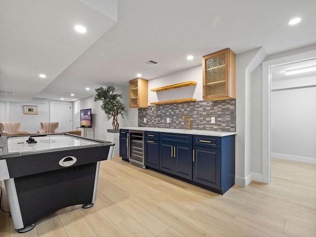 game room with beverage cooler, sink, and light wood-type flooring