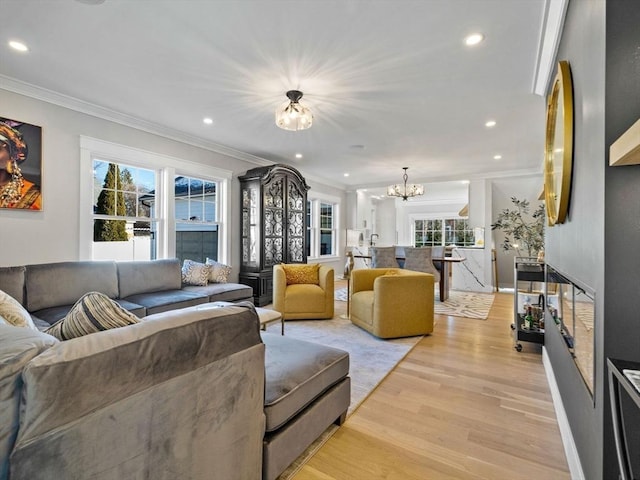 living room featuring ornamental molding, an inviting chandelier, and light hardwood / wood-style flooring