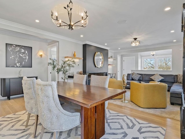 dining area featuring crown molding, an inviting chandelier, and light hardwood / wood-style floors