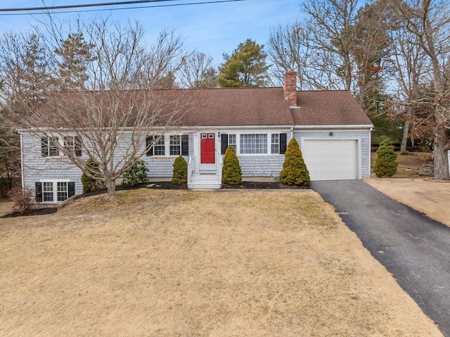 view of front facade featuring a garage, a shingled roof, driveway, a chimney, and a front yard