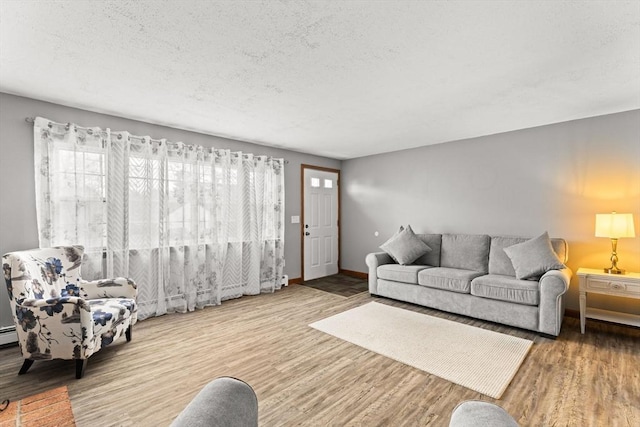 living room featuring a textured ceiling, baseboards, and wood finished floors