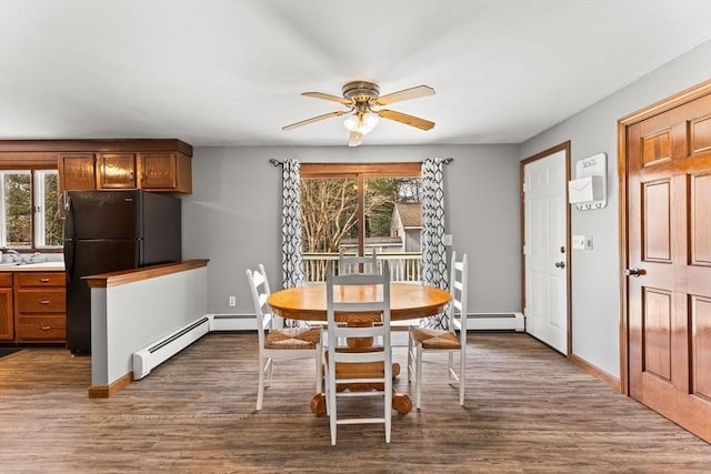 dining area with a baseboard heating unit, ceiling fan, dark wood-style flooring, and baseboards