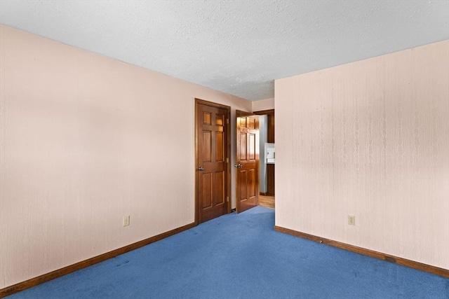 spare room with carpet floors, baseboards, and a textured ceiling