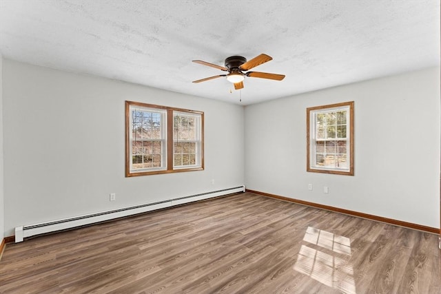 unfurnished room featuring a baseboard heating unit, ceiling fan, a textured ceiling, wood finished floors, and baseboards