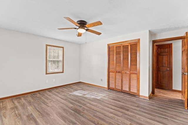 unfurnished bedroom featuring ceiling fan, a closet, baseboards, and wood finished floors