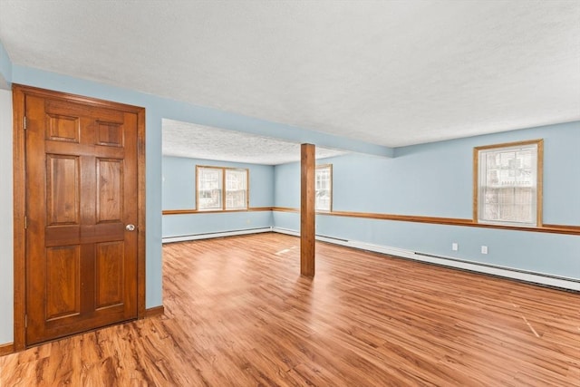 unfurnished room featuring a baseboard radiator, a textured ceiling, baseboards, and wood finished floors