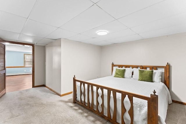 bedroom featuring a paneled ceiling, carpet, a baseboard heating unit, and baseboards