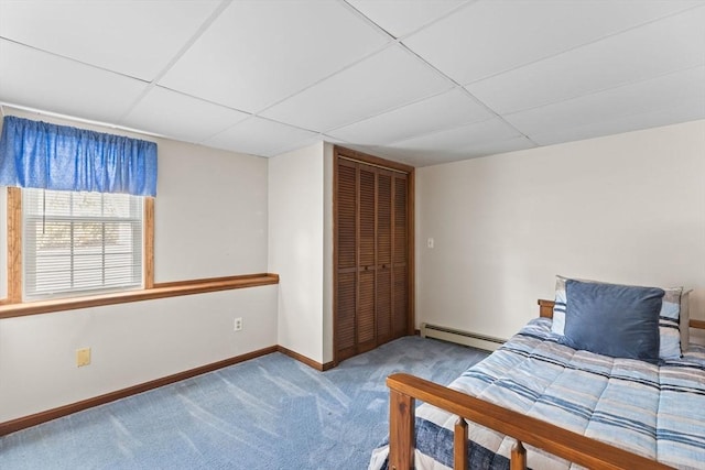 unfurnished bedroom featuring a paneled ceiling, a baseboard heating unit, carpet flooring, baseboards, and a closet