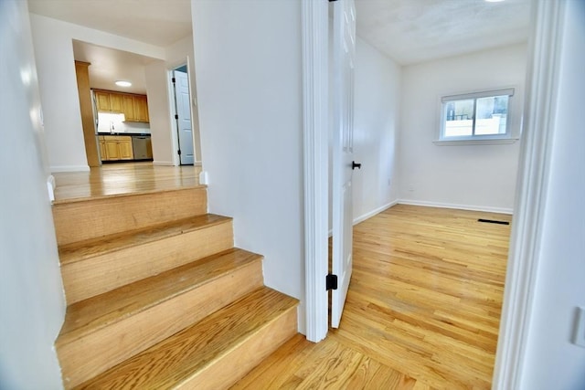 staircase featuring wood-type flooring and sink