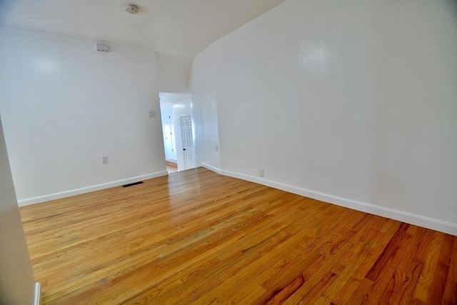 empty room with light hardwood / wood-style floors and vaulted ceiling