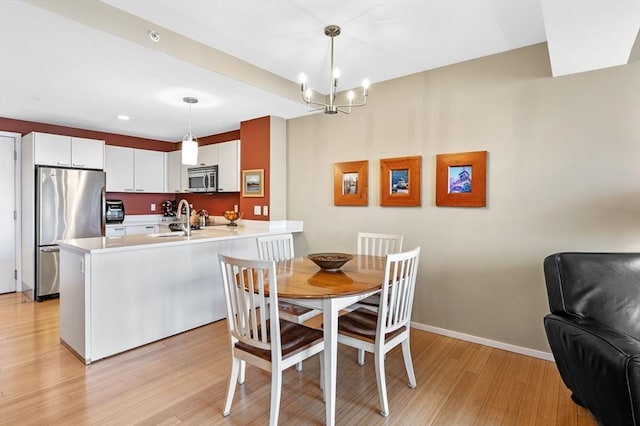 kitchen featuring a peninsula, appliances with stainless steel finishes, light wood-type flooring, and a sink