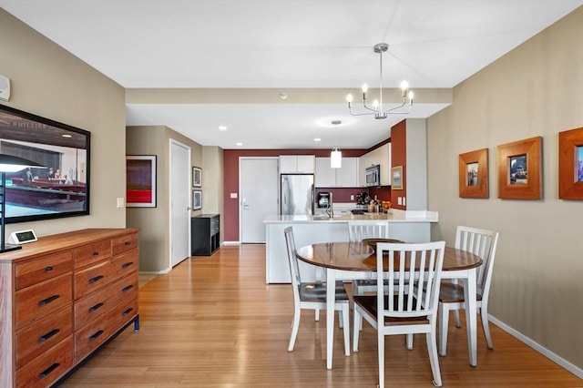 dining room featuring light wood-type flooring, a notable chandelier, baseboards, and recessed lighting