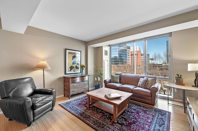 living room featuring light wood-type flooring, visible vents, baseboards, and a view of city