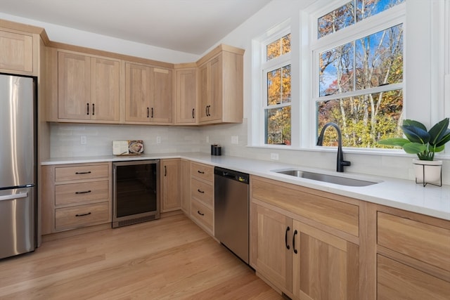 kitchen featuring light brown cabinets, light hardwood / wood-style flooring, stainless steel appliances, wine cooler, and sink