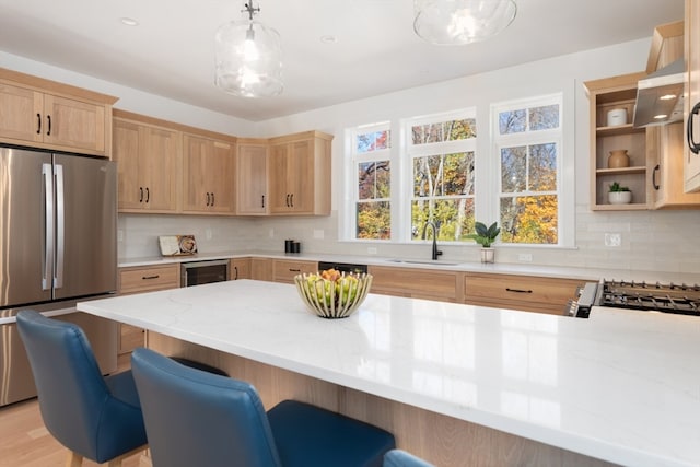 kitchen featuring hanging light fixtures, a breakfast bar area, stainless steel appliances, sink, and light stone counters