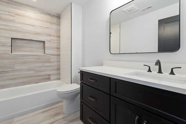 full bathroom featuring vanity, hardwood / wood-style floors, tiled shower / bath combo, and toilet