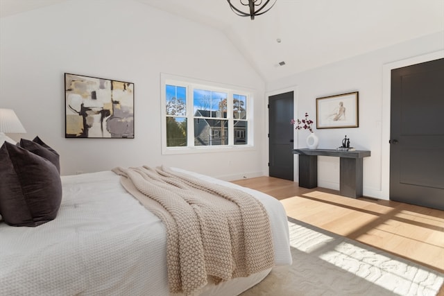 bedroom with light hardwood / wood-style floors and lofted ceiling