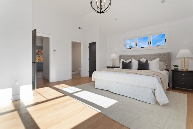 bedroom with a notable chandelier, hardwood / wood-style floors, and ensuite bath