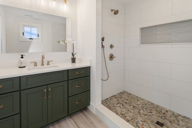 bathroom featuring vanity, a tile shower, and wood-type flooring