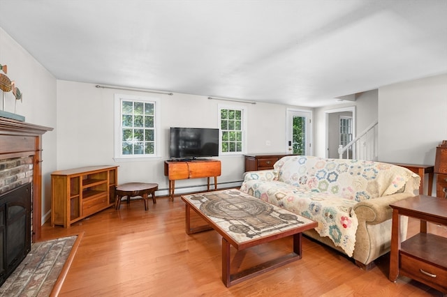 living room featuring a baseboard radiator, a fireplace, and light wood-type flooring