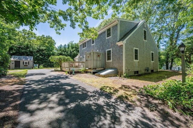 view of front of home with a wooden deck and a storage shed