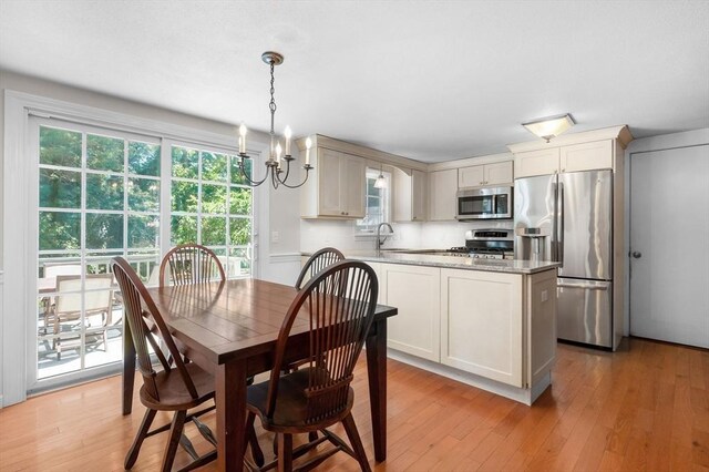 dining space featuring an inviting chandelier, sink, and light hardwood / wood-style floors