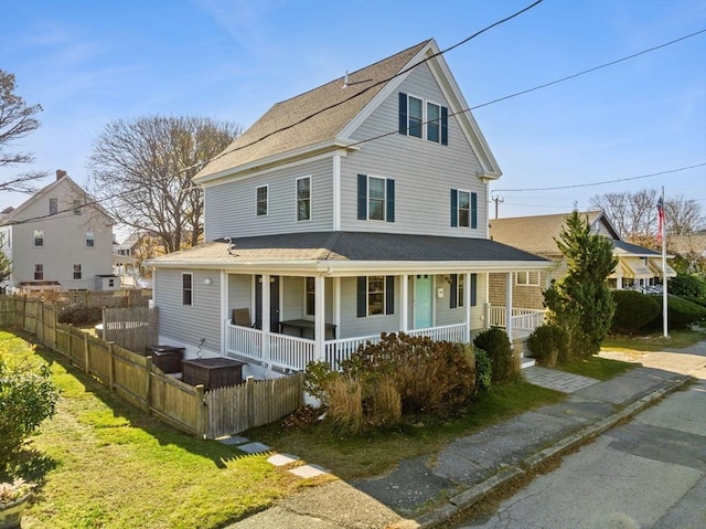 view of front facade featuring a porch, roof with shingles, and fence