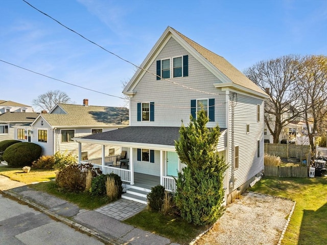 view of front of home featuring roof with shingles, a porch, and fence