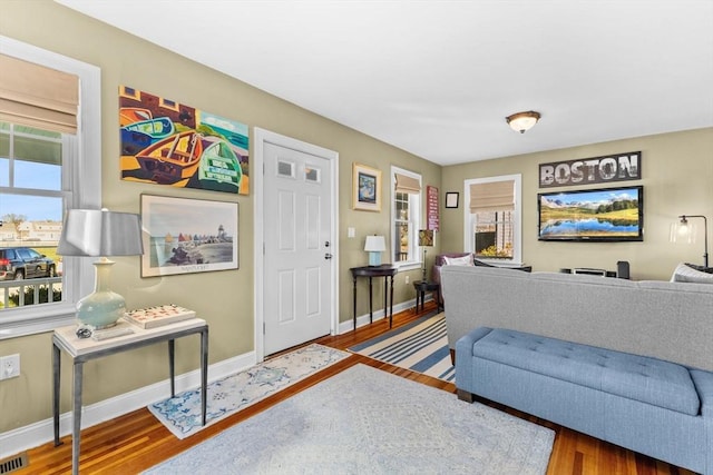 living room featuring visible vents, baseboards, and wood finished floors