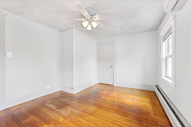 spare room featuring a baseboard heating unit, light wood-style flooring, a wall mounted AC, and baseboards
