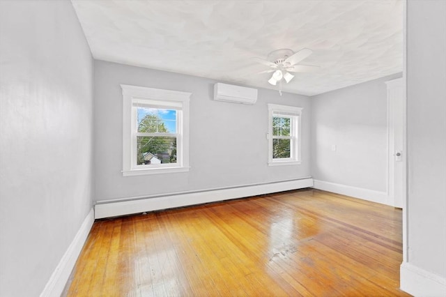 spare room with baseboard heating, plenty of natural light, baseboards, and hardwood / wood-style floors