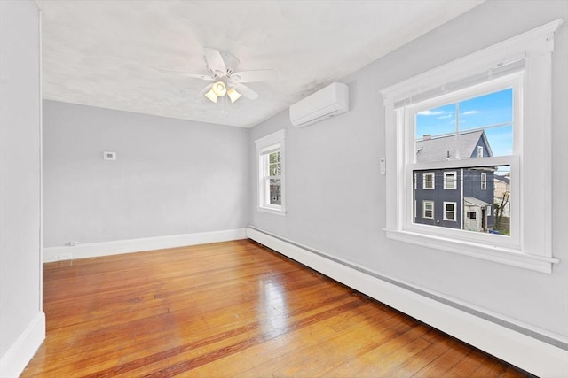unfurnished room featuring an AC wall unit, a baseboard radiator, baseboards, wood finished floors, and ceiling fan