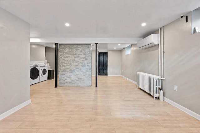finished basement with radiator, an AC wall unit, separate washer and dryer, light wood-type flooring, and recessed lighting