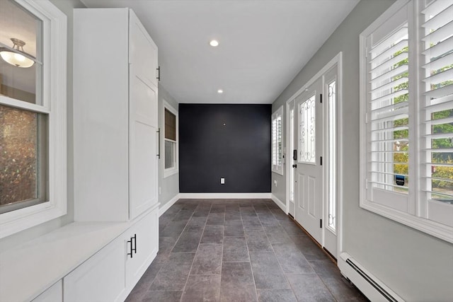 foyer entrance with baseboard heating, recessed lighting, baseboards, and dark stone finish floors