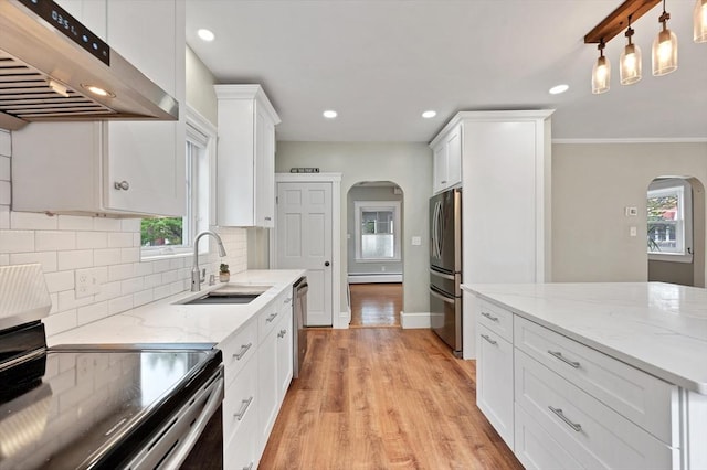 kitchen featuring arched walkways, stainless steel appliances, under cabinet range hood, a sink, and recessed lighting