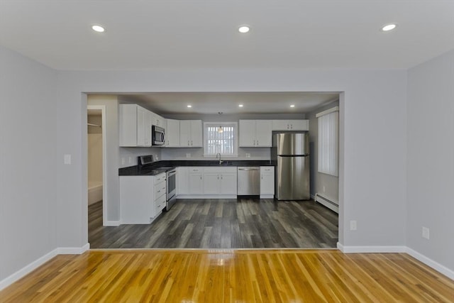 kitchen with stainless steel appliances, dark wood-type flooring, a sink, baseboards, and baseboard heating